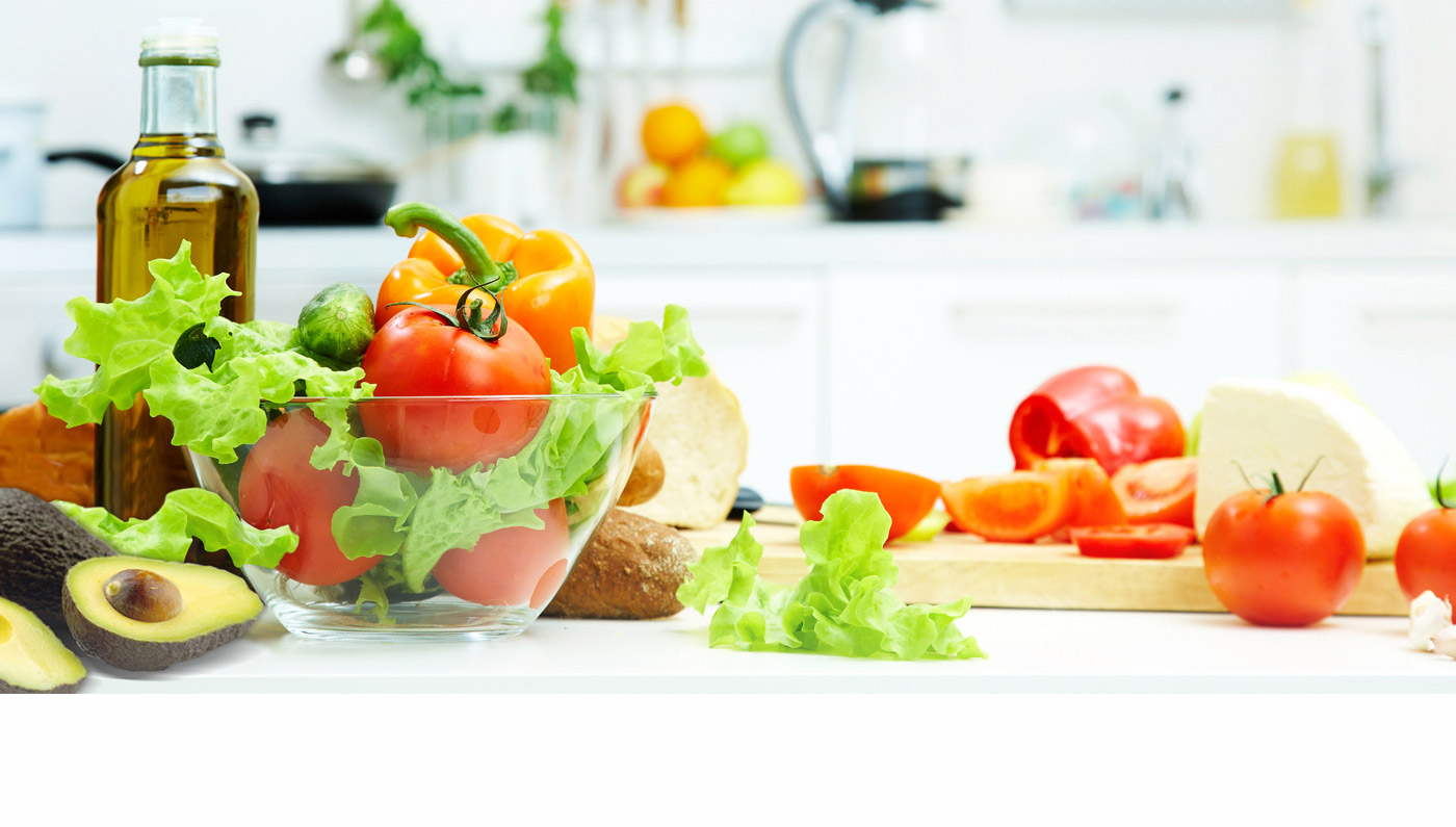 Verduras frescas y aceite de oliva sobre una mesa de cocina con luz brillante